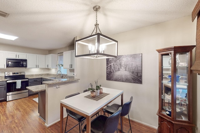 1211 Leeward Ln, Wylie, TX 75098 - kitchen with electric range, black microwave, a sink, light wood-style flooring, and white cabinets