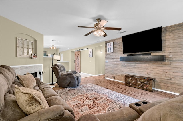 4318 Quail Run Rd, Sherman, TX 75092 - living area with a barn door, ceiling fan, baseboards, wooden walls, and wood finished floors