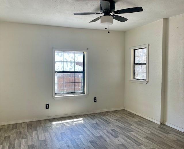 4825 Fitzhugh Ave, Fort Worth, TX 76105 - empty room featuring wood finished floors, a ceiling fan, baseboards, and a textured ceiling