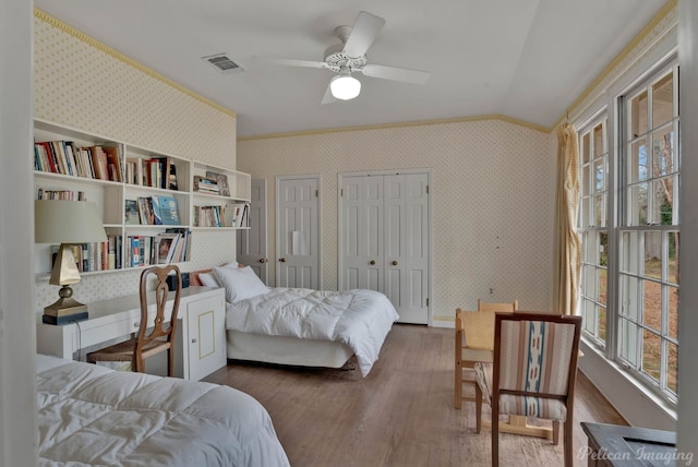 514 Pierremont Cir, Shreveport, LA 71106 - bedroom featuring multiple windows, vaulted ceiling, wood finished floors, wallpapered walls, and two closets