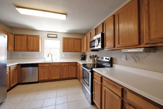 1446 Foxwood Ln, Rockwall, TX 75032 - kitchen featuring stainless steel appliances, a sink, brown cabinets, and light countertops