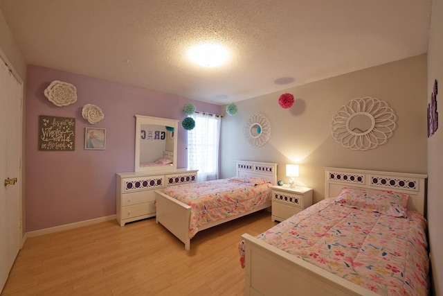 1446 Foxwood Ln, Rockwall, TX 75032 - bedroom with light wood-style floors, a textured ceiling, and baseboards