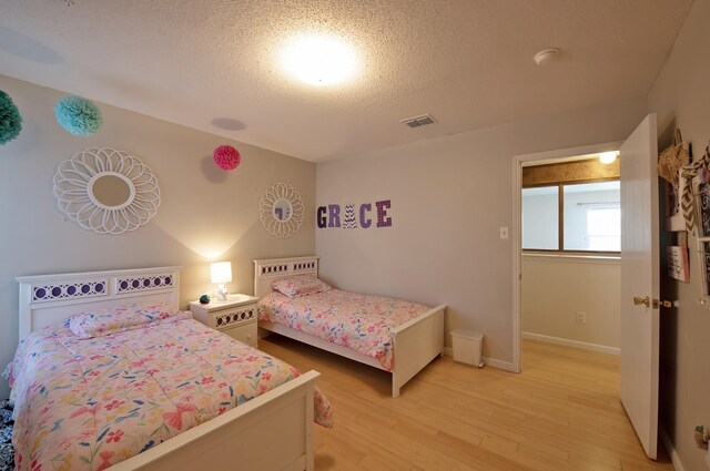 1446 Foxwood Ln, Rockwall, TX 75032 - bedroom with light wood-type flooring, baseboards, and a textured ceiling