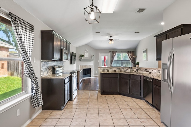 1433 Wind Dancer Trl, Fort Worth, TX 76131 - kitchen featuring appliances with stainless steel finishes, a peninsula, ceiling fan, decorative backsplash, and a tile fireplace