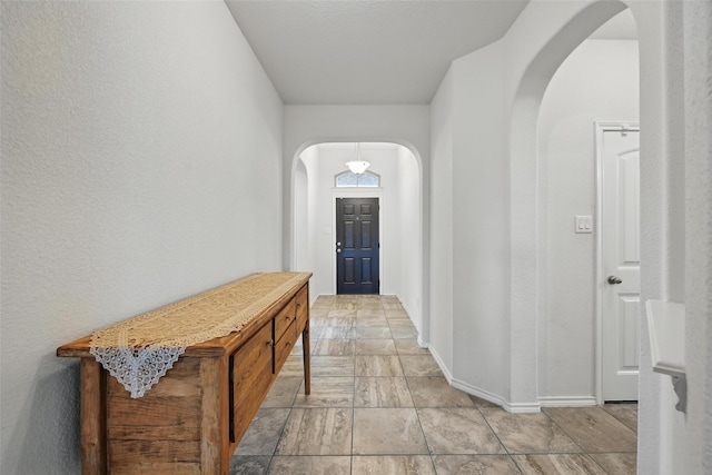 11512 Starlight Ranch Trl, Fort Worth, TX 76052 - hall with arched walkways, baseboards, and light stone finish floors