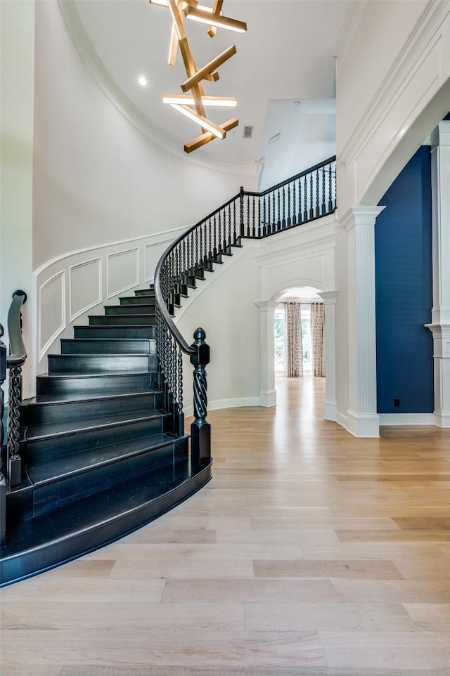 805 Cross Ln, Southlake, TX 76092 - staircase featuring ornate columns, a towering ceiling, a chandelier, wood finished floors, and ornamental molding