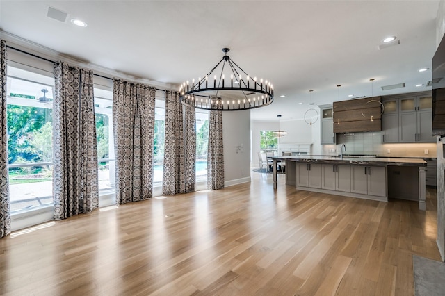 805 Cross Ln, Southlake, TX 76092 - kitchen with a chandelier, decorative backsplash, light wood finished floors, dark countertops, and a center island with sink