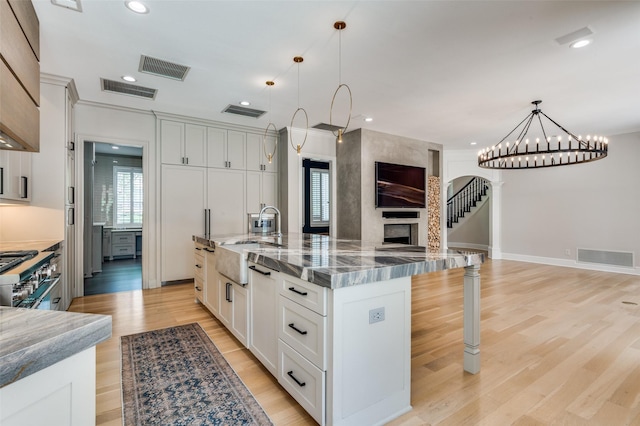 805 Cross Ln, Southlake, TX 76092 - kitchen featuring a sink, open floor plan, a breakfast bar area, dark stone counters, and light wood finished floors