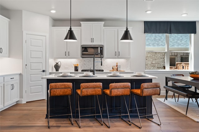 3105 Patrinia St, Royse City, TX 75189 - kitchen featuring stainless steel microwave, an island with sink, white cabinetry, backsplash, and recessed lighting