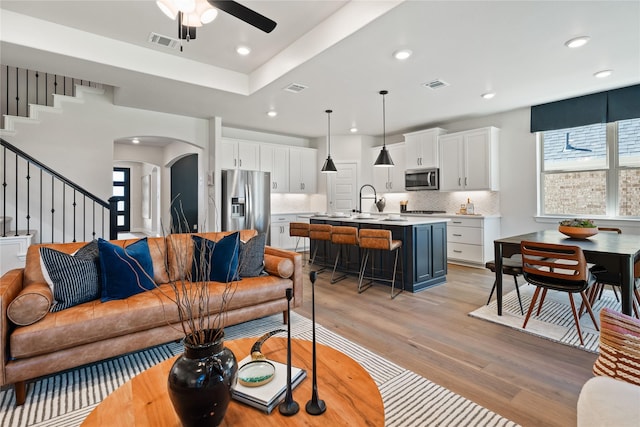 3105 Patrinia St, Royse City, TX 75189 - living area featuring arched walkways, light wood finished floors, stairway, ceiling fan, and recessed lighting