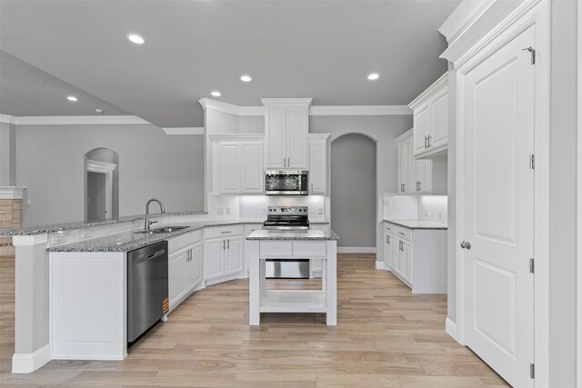 833 Haley, Springtown, TX 76082 - kitchen with stainless steel appliances, a sink, arched walkways, ornamental molding, and a peninsula