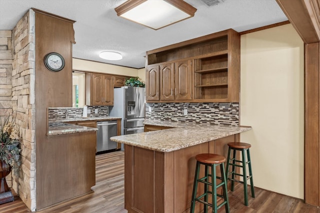 507 Cedar St, Edgewood, TX 75117 - kitchen featuring appliances with stainless steel finishes, backsplash, a peninsula, open shelves, and light wood finished floors