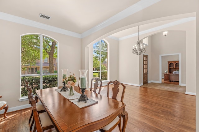 15372 Mountain View Ln, Frisco, TX 75035 - dining room with healthy amount of natural light, arched walkways, light wood-type flooring, crown molding, and a chandelier