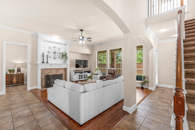 15372 Mountain View Ln, Frisco, TX 75035 - tiled living area with ceiling fan, stairs, arched walkways, a tiled fireplace, and ornamental molding