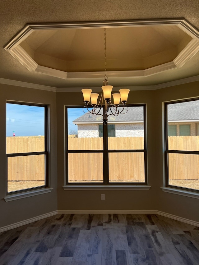 554 Calla Lily Dr, Tolar, TX 76476 - unfurnished dining area featuring a tray ceiling, a chandelier, healthy amount of natural light, ornamental molding, and dark wood-style flooring