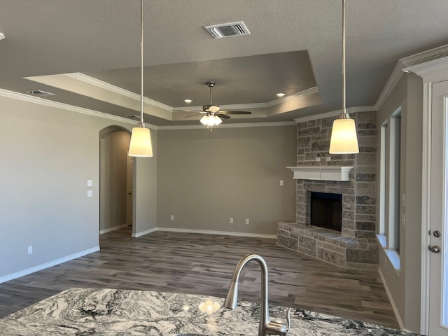 554 Calla Lily Dr, Tolar, TX 76476 - kitchen with a tray ceiling, wood finished floors, ornamental molding, arched walkways, and a stone fireplace