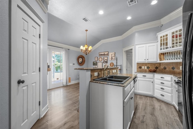 10513 Rayburn Way, Waco, TX 76708 - kitchen featuring a sink, backsplash, a kitchen island with sink, white cabinets, and ornamental molding