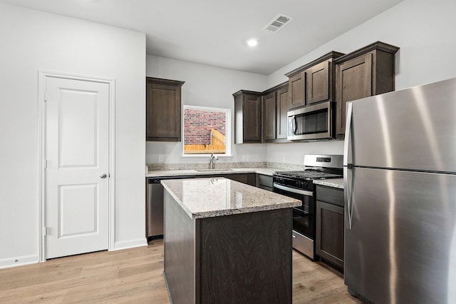 409 Gib Woodall Dr, Venus, TX 76084 - kitchen featuring appliances with stainless steel finishes, a center island, a sink, dark brown cabinetry, and light wood finished floors