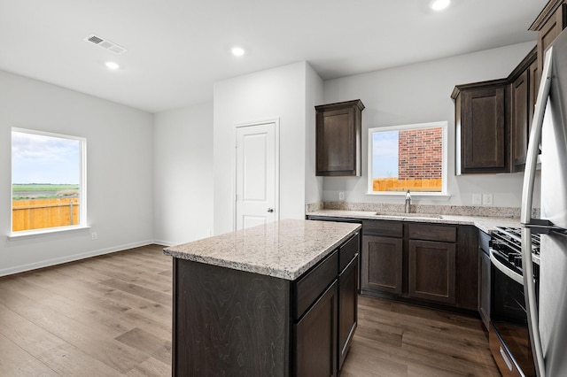 409 Gib Woodall Dr, Venus, TX 76084 - kitchen featuring a sink, range with gas stovetop, a center island, wood finished floors, and light stone countertops