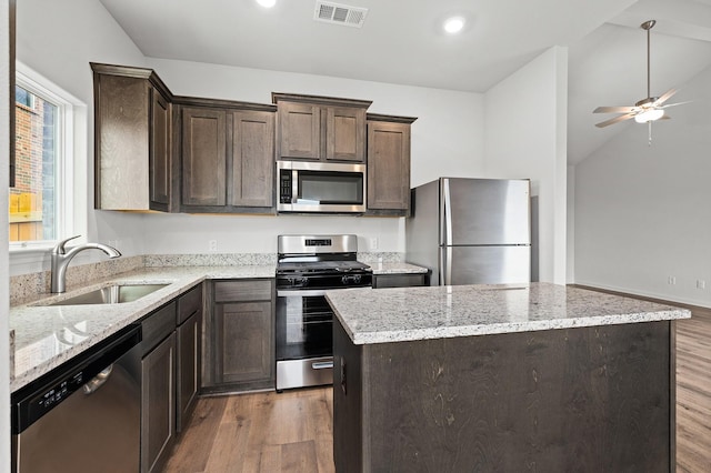 409 Gib Woodall Dr, Venus, TX 76084 - kitchen featuring stainless steel appliances, a sink, wood finished floors, dark brown cabinetry, and a kitchen island