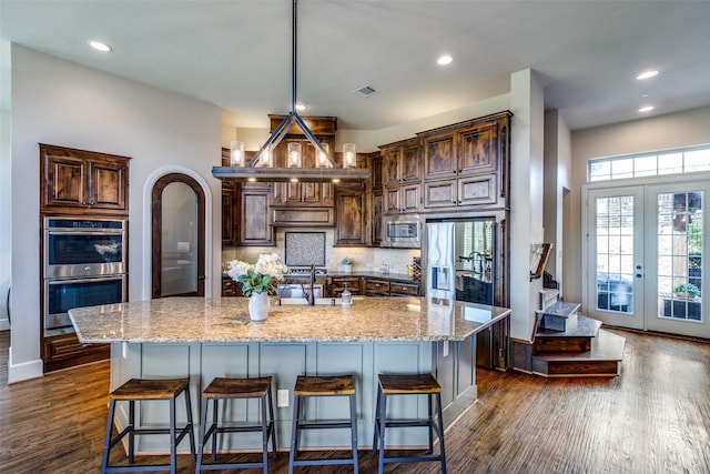4540 Honeyvine Ln, Prosper, TX 75078 - kitchen featuring appliances with stainless steel finishes, a sink, light stone counters, a breakfast bar area, and recessed lighting