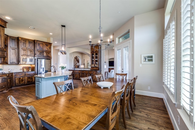 4540 Honeyvine Ln, Prosper, TX 75078 - dining area with dark wood-type flooring, arched walkways, french doors, a chandelier, and baseboards