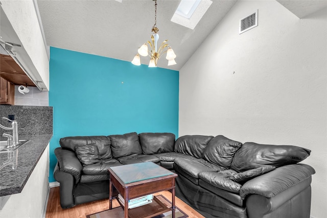2135 Rose Cliff Ln, Carrollton, TX 75007 - living room with vaulted ceiling, a skylight, wood finished floors, and a chandelier