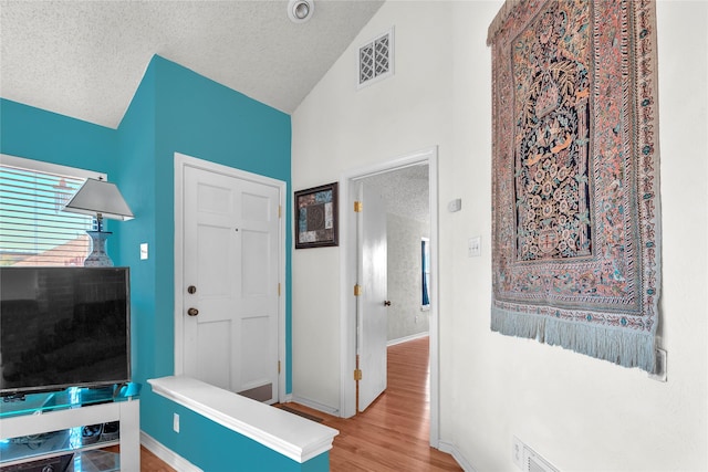 2135 Rose Cliff Ln, Carrollton, TX 75007 - entrance foyer featuring a textured ceiling, wood finished floors, baseboards, and high vaulted ceiling