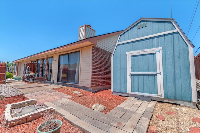 2135 Rose Cliff Ln, Carrollton, TX 75007 - back of property with a chimney, a patio area, and brick siding