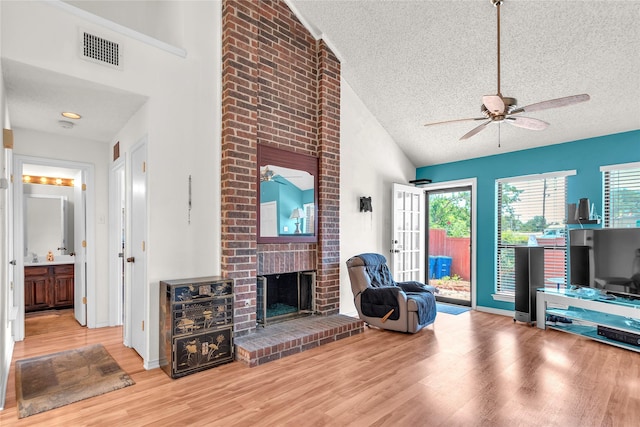 2135 Rose Cliff Ln, Carrollton, TX 75007 - living area with a textured ceiling, ceiling fan, wood finished floors, a brick fireplace, and high vaulted ceiling