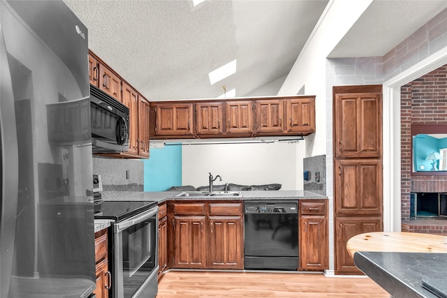 2135 Rose Cliff Ln, Carrollton, TX 75007 - kitchen with black appliances, a sink, brown cabinets, a skylight, and lofted ceiling