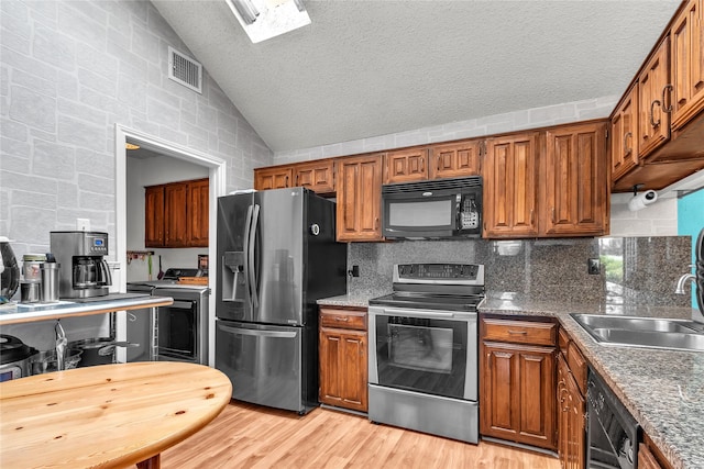 2135 Rose Cliff Ln, Carrollton, TX 75007 - kitchen featuring black appliances, washer / dryer, a sink, vaulted ceiling, and light wood-style flooring