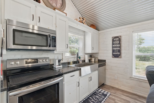 18230 Interstate 20, Cisco, TX 76437 - kitchen featuring appliances with stainless steel finishes, a sink, dark countertops, white cabinets, and wood walls