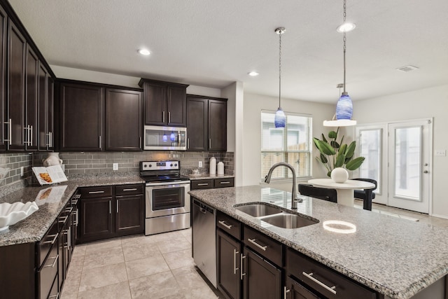 3740 Holly Brook Dr, Fort Worth, TX 76244 - kitchen featuring a sink, appliances with stainless steel finishes, backsplash, dark brown cabinetry, and light stone counters