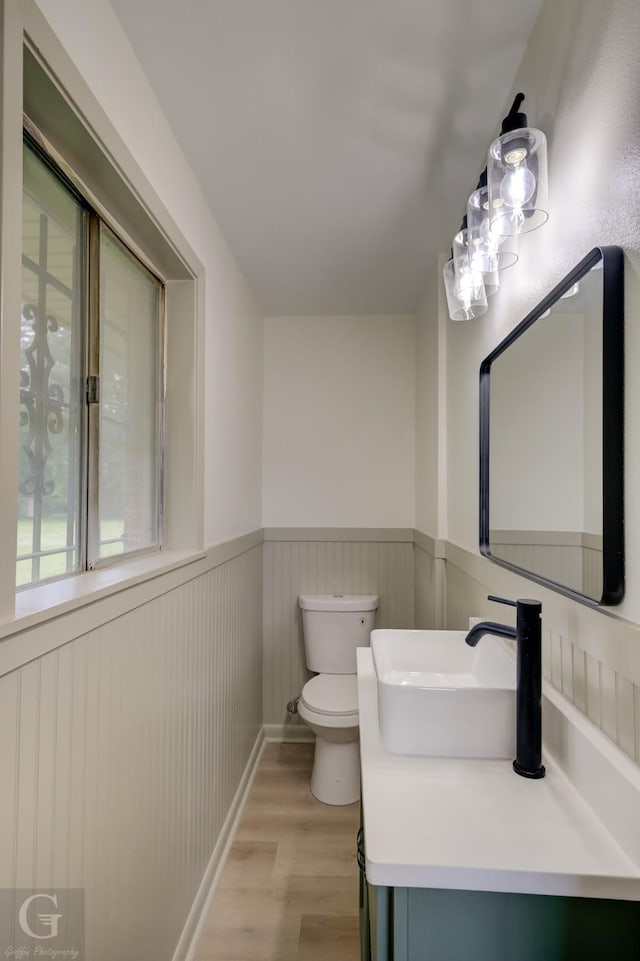 808 E St, Minden, LA 71055 - half bathroom with wood finished floors, toilet, wainscoting, and vanity
