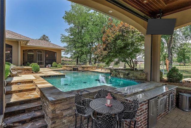 609 Enchanted Ln, Bossier City, LA 71111 - view of swimming pool with exterior kitchen, a pool with connected hot tub, a sunroom, and a patio area