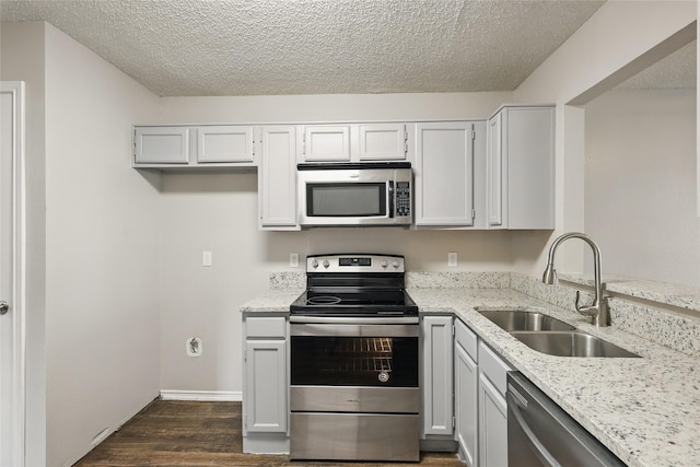 703 Inglewood Trl, Desoto, TX 75115 - kitchen featuring stainless steel appliances, a sink, dark wood-style floors, light stone counters, and a textured ceiling