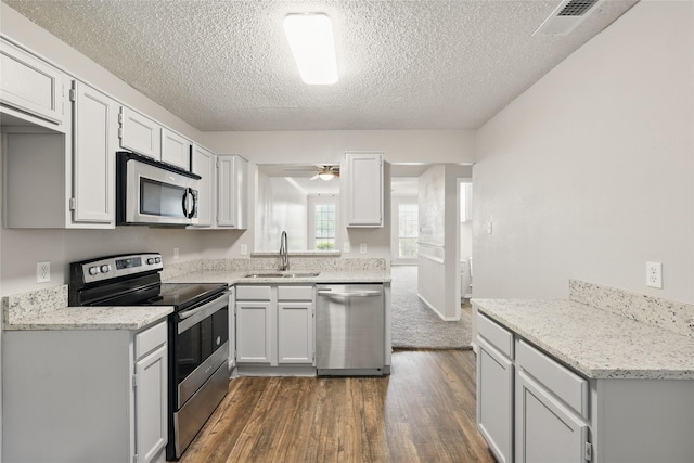 703 Inglewood Trl, Desoto, TX 75115 - kitchen featuring appliances with stainless steel finishes, a sink, dark wood-style floors, a textured ceiling, and ceiling fan