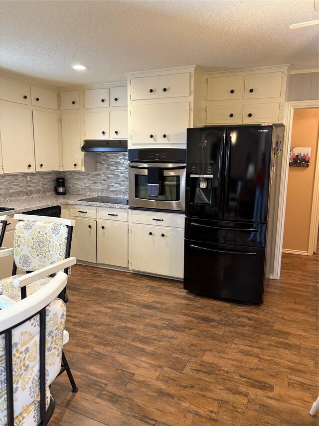 1308 Houston St, Sulphur Springs, TX 75482 - kitchen with black appliances, a textured ceiling, decorative backsplash, dark wood-style floors, and white cabinets