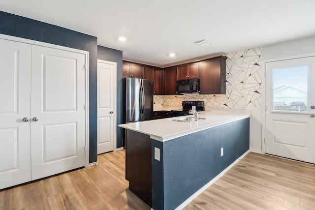 5431 Longshadow Dr, Princeton, TX 75407 - kitchen with black appliances, light wood finished floors, tasteful backsplash, dark brown cabinetry, and a peninsula