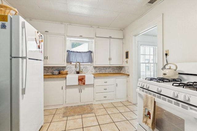 812 N 32nd St, Waco, TX 76707 - kitchen with white appliances, a sink, white cabinets, and light tile patterned floors