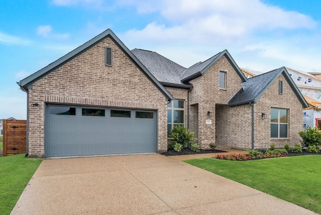 1432 Casting Rdg, Mesquite, TX 75181 - french country style house featuring concrete driveway, brick siding, an attached garage, a front lawn, and a shingled roof