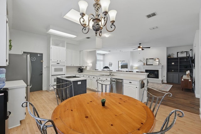 4516 Ridgepointe Dr, The Colony, TX 75056 - dining space featuring light wood-style flooring, a chandelier, a ceiling fan, and a glass covered fireplace