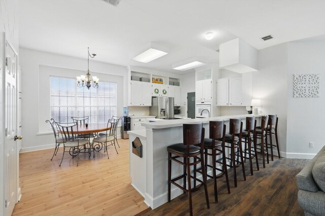4516 Ridgepointe Dr, The Colony, TX 75056 - kitchen with a peninsula, light wood-style floors, stainless steel fridge with ice dispenser, and a chandelier