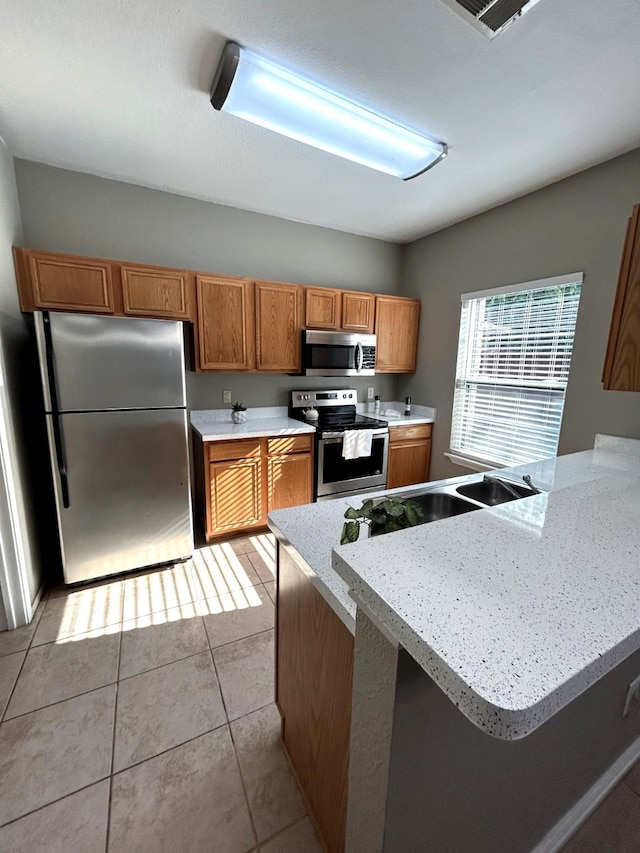 1505 Yellowbird Ct, Desoto, TX 75115 - kitchen with stainless steel appliances, brown cabinets, light countertops, and a peninsula