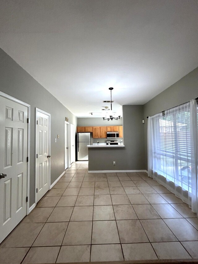 1505 Yellowbird Ct, Desoto, TX 75115 - kitchen featuring appliances with stainless steel finishes, a chandelier, light tile patterned floors, a peninsula, and pendant lighting