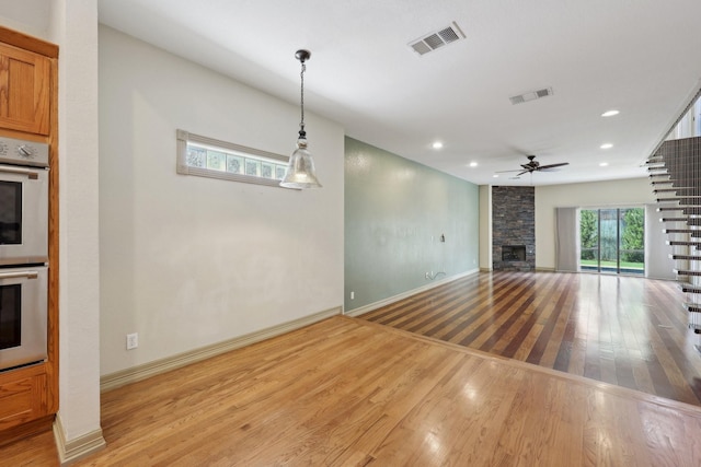 3804 Mattison Ave, Fort Worth, TX 76107 - unfurnished living room with wood finished floors, a stone fireplace, ceiling fan, and recessed lighting