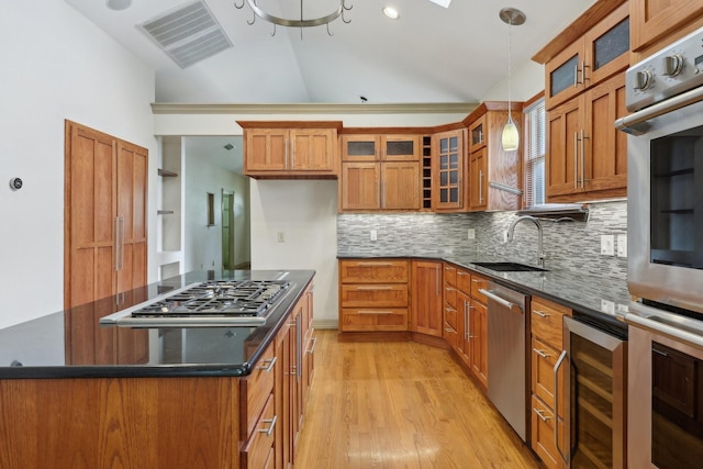 3804 Mattison Ave, Fort Worth, TX 76107 - kitchen featuring stainless steel appliances, brown cabinetry, vaulted ceiling, backsplash, and light wood finished floors