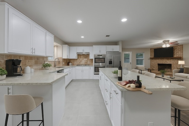 1624 Summer Place Cir, Irving, TX 75062 - kitchen with stainless steel appliances, a breakfast bar, backsplash, a fireplace, and recessed lighting