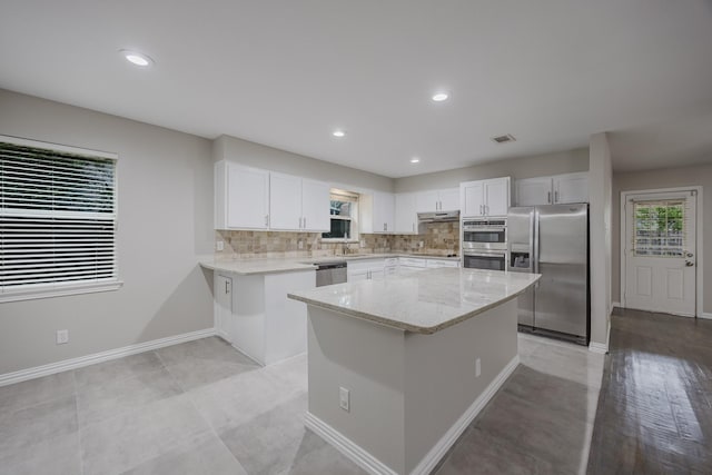 1624 Summer Place Cir, Irving, TX 75062 - kitchen featuring stainless steel appliances, under cabinet range hood, light stone countertops, white cabinetry, and tasteful backsplash